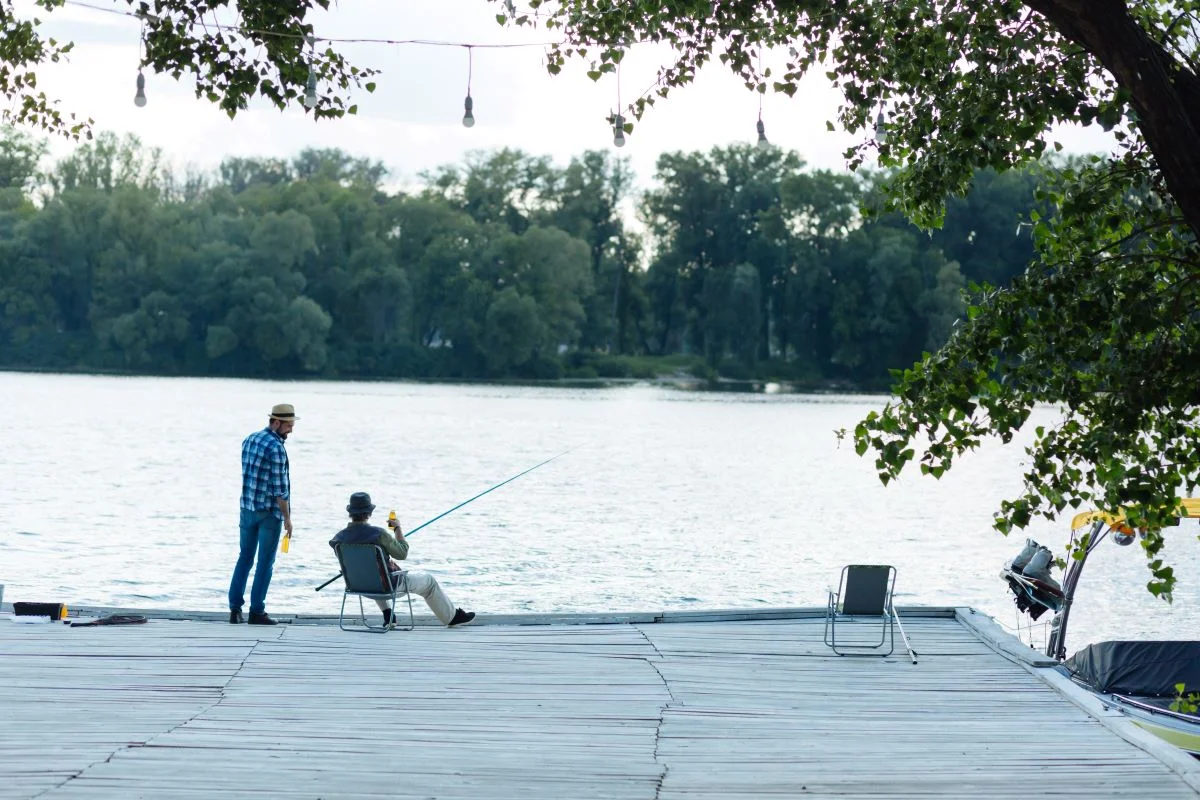 man-standing-near-old-male-sitting-and-fishing-2023-11-27-05-12-04-utc